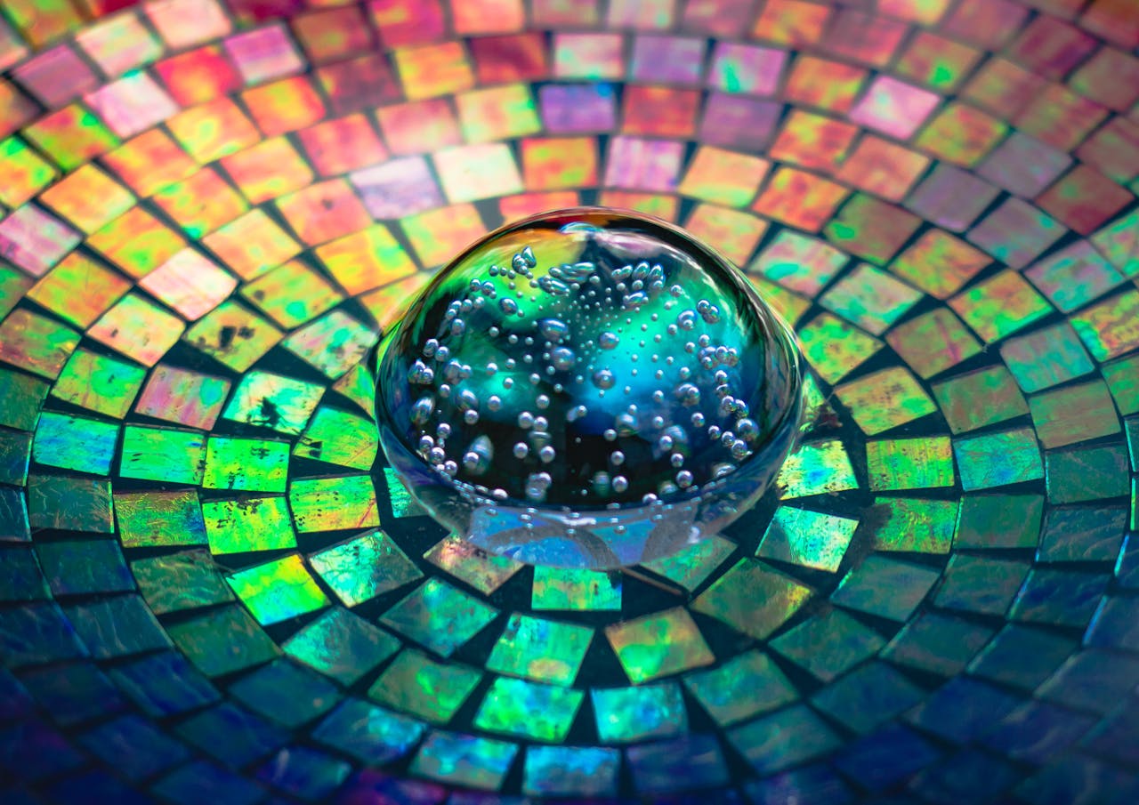 Colorful mosaic pattern with a glass bubble sphere reflecting vibrant rainbow colors.